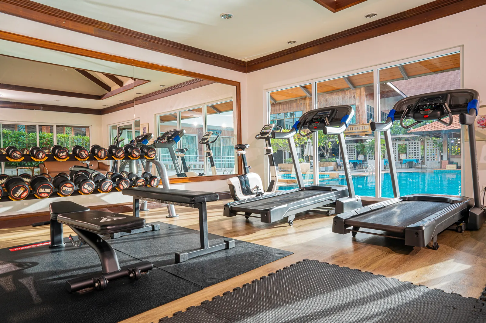 Fitness room at Khum Phucome Hotel Chiang Mai, with treadmills and free weights overlooking the pool